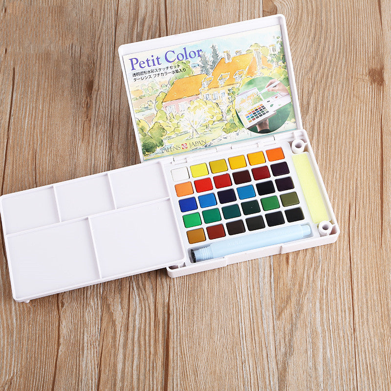 Watercolor paint set with color chart on a wooden surface