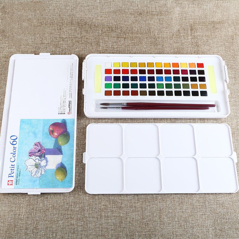 Watercolor set with paint pots, brush, and color chart on a textured surface