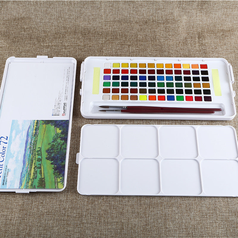 Watercolor paint set with color chart, paint palette, and brush on a textured surface