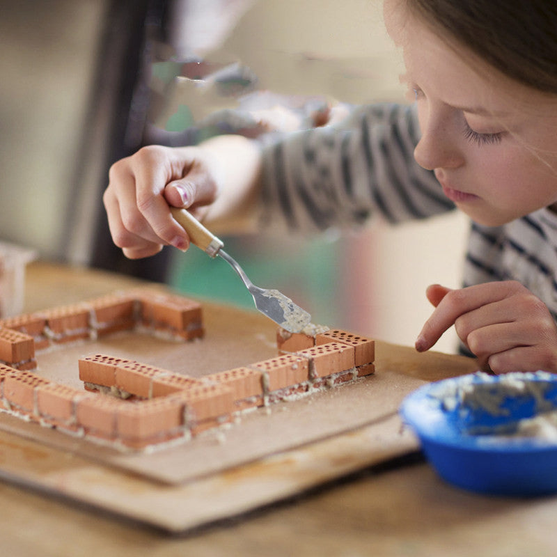 Child building with small bricks on a wooden surface
