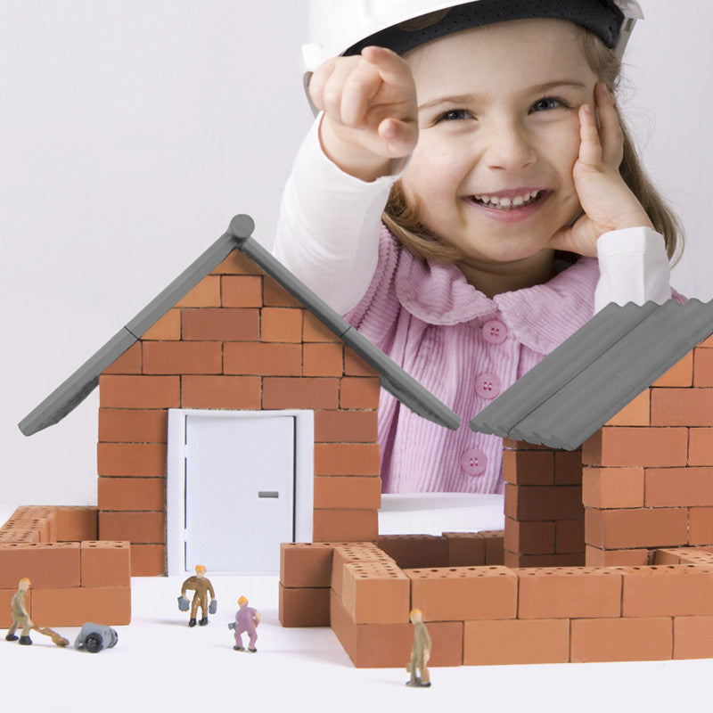 Child playing with toy building blocks and miniature figures on a white background