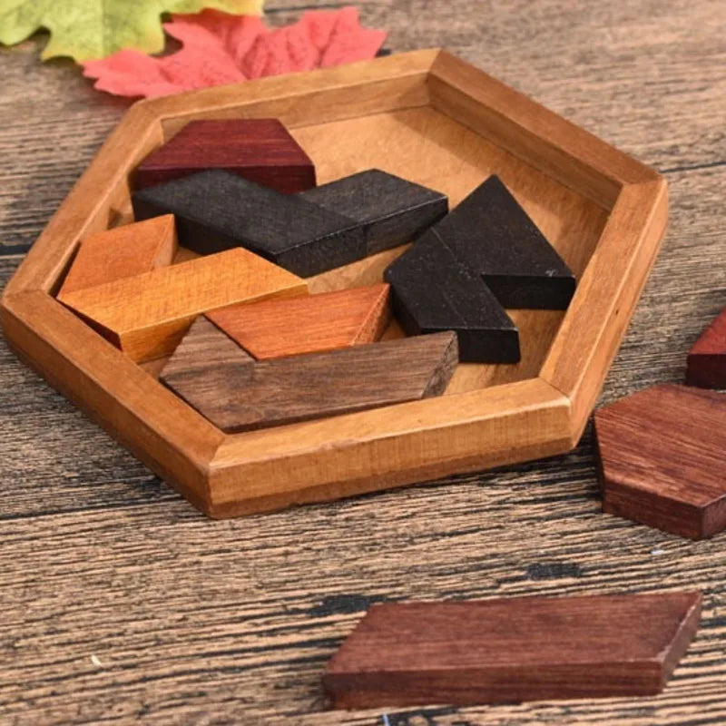 Wooden puzzle pieces in a hexagonal wooden tray on a wooden surface with leaves.