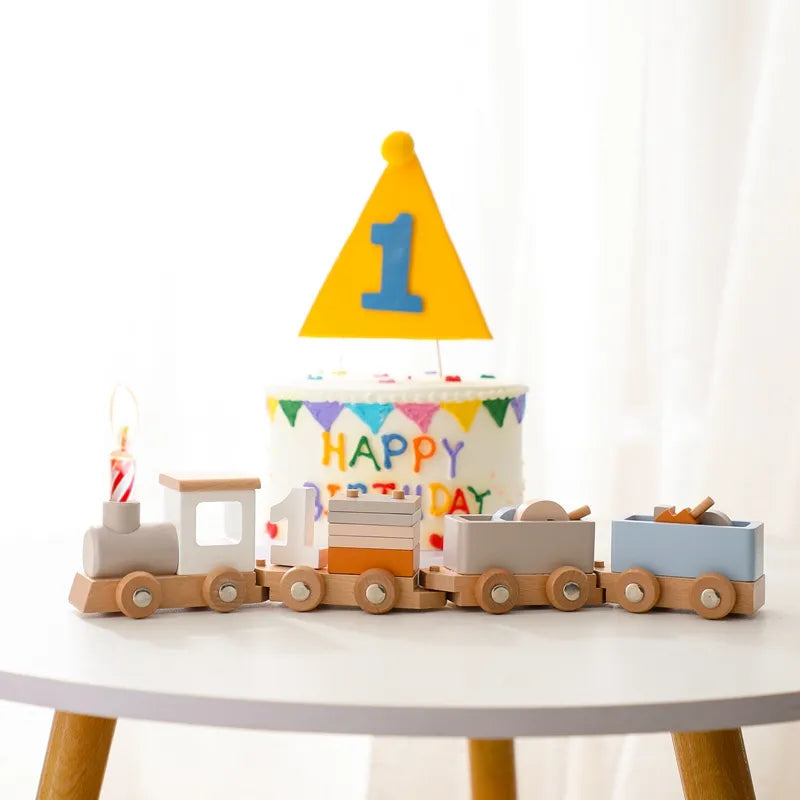Children's birthday cake with colorful decorations and a wooden train on a white table.
