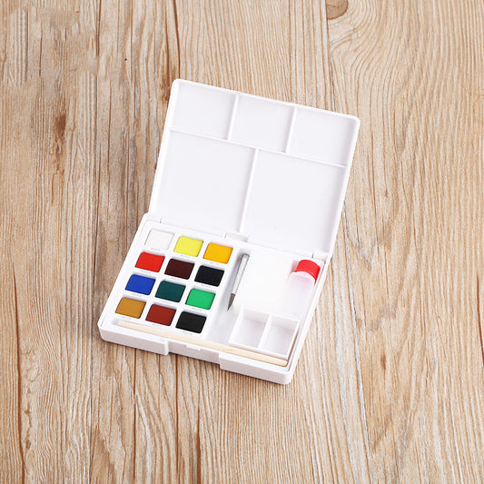 Open watercolor set with paint pans on a wooden surface