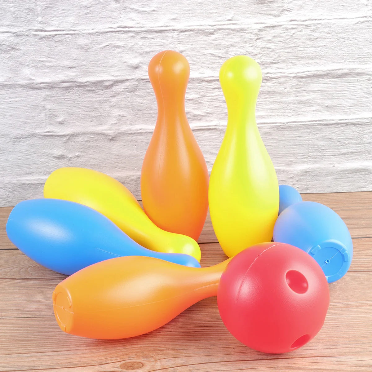 Colorful plastic bowling pins and ball on a wooden surface with a light wood panel background