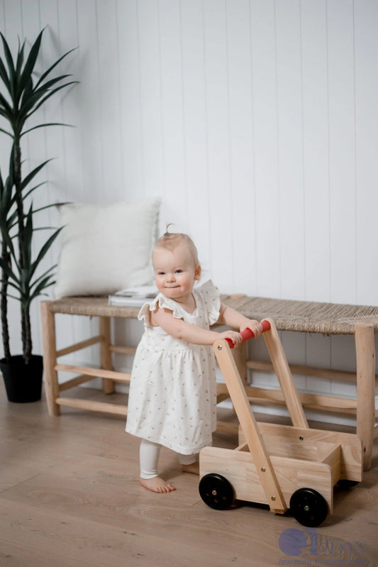 Child playing with a wooden toy in a room with a white wall and plant.