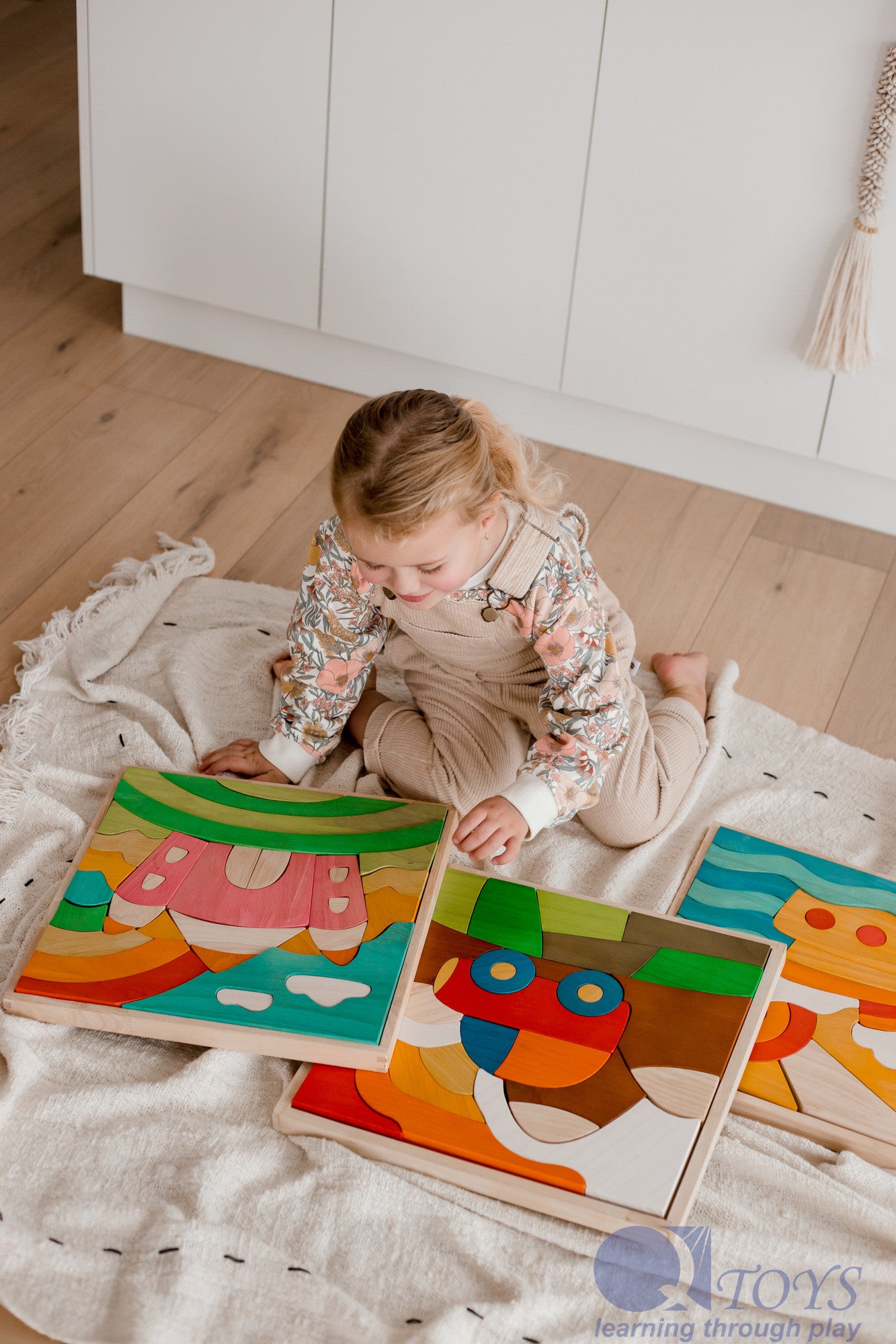 Child playing with colorful wooden puzzles on a light-colored rug.
