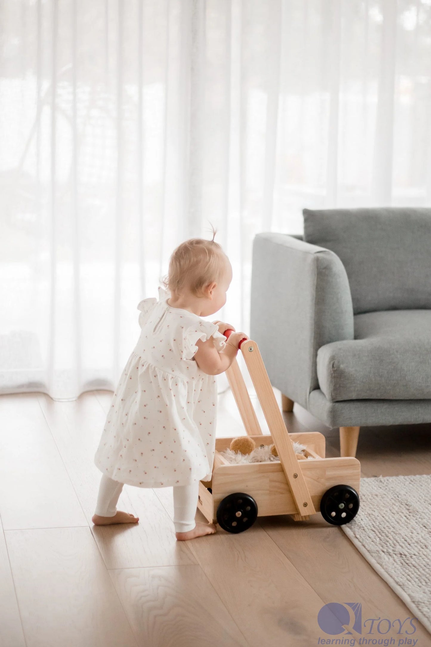 Child playing with a wooden toy in a room with light-colored walls and furniture.
